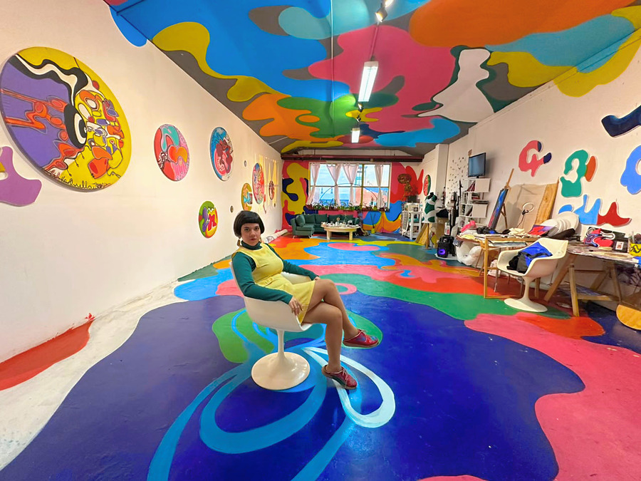 Ornella Ruiz Díaz sentada en su estudio de Barracas, Buenos Aires, con el piso, los muros y el cielorraso pintados con formas orgánicas de color